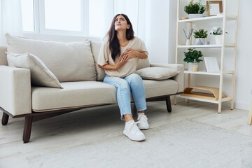 Obraz premium Woman sitting on sofa at home arm and shoulder pain, muscle sprain and joint pain, calcium problems in bones