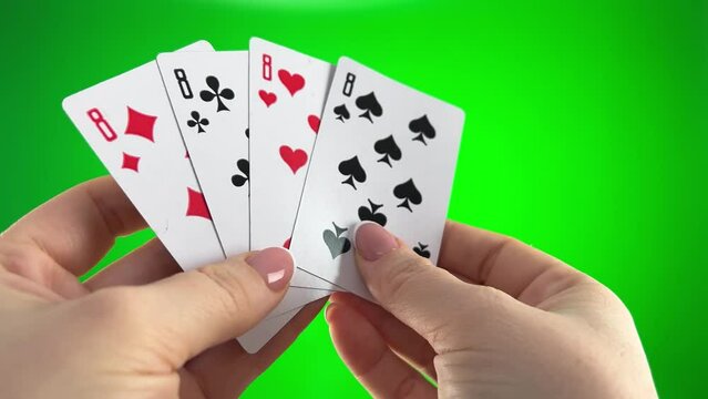 Hand holding four eights on a green background close-up female hands with french manicure woman sorts through cards, examines them folds and spreads out like fan four cards left of same suit