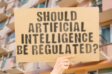 The question " Should artificial intelligence be regulated? " is on a banner in men's hands with blurred background. Negotiation. Service. Requirement. Ethical. Computer. Digital. Administration