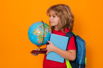Fototapeta premium School kid hold world globe and book. Back to school. Funny little student boy from elementary school with book. Pupil on studio isolated background.