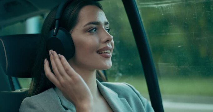 Buisnees woman in car wearing wireless headphones speaks by phone having call from colleagues. Calm woman pressing sounds relived girl heading meeting appointment .