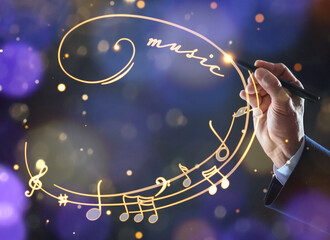 Man with pen drawing staff with music notes and symbols on color background, closeup
