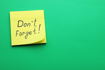 Paper note with phrase Don't Forget on green background, top view. Space for text