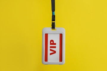 White plastic vip badge hanging on yellow background - obrazy, fototapety, plakaty
