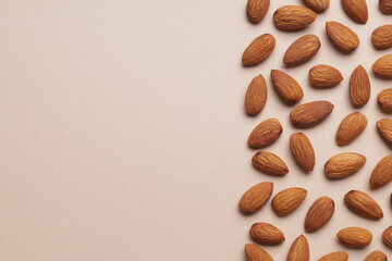 Delicious raw almonds on beige background, flat lay. Space for text