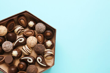 Box of delicious chocolate candies on light blue background, top view. Space for text