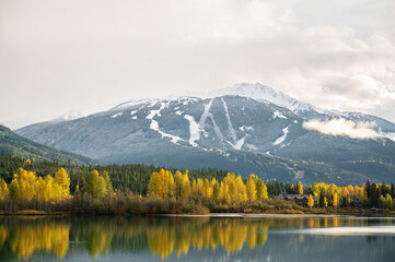 Green Lake in autumn with fall colours and a snow covered Whistler Mountain.  Whistler BC, Canada.