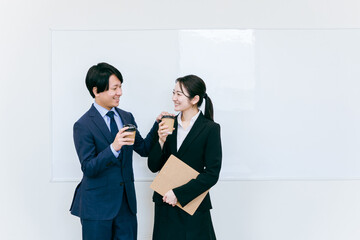コーヒーを飲んで休憩するスーツ姿のビジネスマン・ビジネスウーマン（笑顔・男女）
