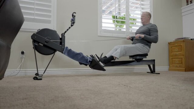 Senior man rowing machine exercise - sliding low angle