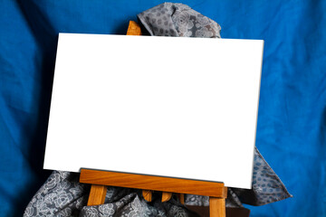Blank horizontal picture without frame on little easel on a blue background. Place to insert a picture