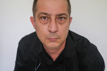 Closeup portrait of caucasian man with baggy eyes looking at the camera, against white background