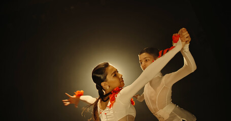 Teen asian kids performing ballroom sport dance on stage with smoked black background on way of becoming professional choreographers - childhood dream, childhood memories concept 