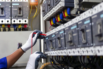 Fototapeta Electricity or electrical maintenance service, Engineer hand checking electric current voltage at circuit breaker terminal and cable wiring check in main power load center distribution board. obraz