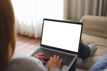 Mockup image of a woman working and typing on laptop computer with blank screen on sofa at home