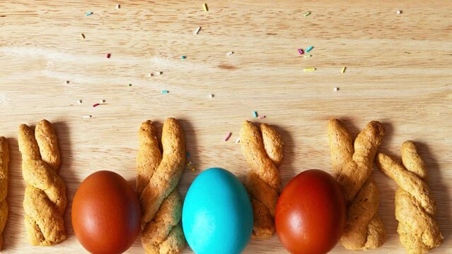 Top view on homemade freshly baked Easter cookies in the form of bunny ears and bright Easter eggs on a wooden table. Empty space for text, close-up, flat lay, mock up. Panoramic movement