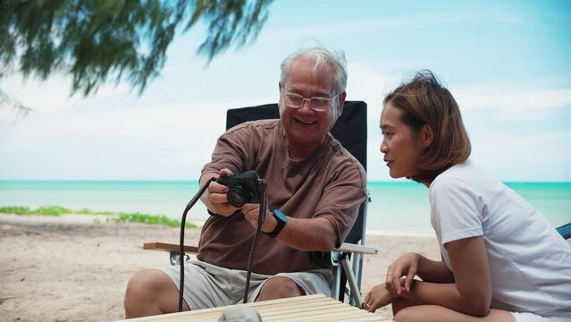 Happy family with senior grandfather picnic and look photo in camera together at seaside. Vacation
