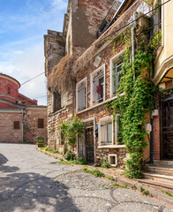 Fototapeta na wymiar Cobblestone alley with beautiful old traditional red bricks houses in old Balat district, on a summer day, Istanbul, Turkey