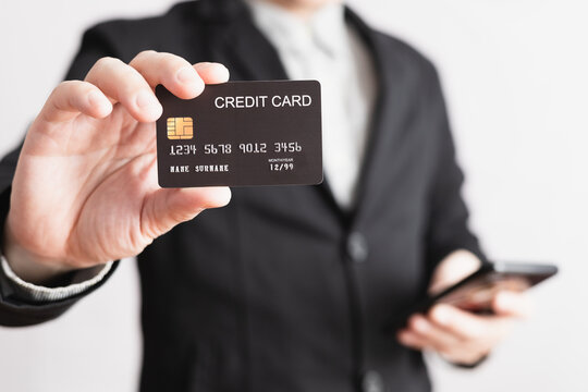 businessman showing a mock-up credit card for shopping to make payment and smartphone.half body. Concept for banner, purchase, commerce, financial, card, money, using technology. selective focus.