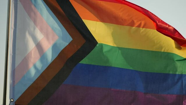 LGBT Rainbow Pride Flag Waving. LGBT, pride, rainbow flag is symbol Gay, Lesbian, Peace, Pride, LGBTQ, Bisexual, Homosexual, Transgender, Love. Rainbow flag waving on sunset, soft focus. Slow motion