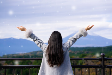 Winter vacation holiday concept, Young asian woman wearing coat and relaxing. She arms raised and enjoying looking view of mountain on winter snow day