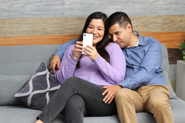 Fototapeta na wymiar Latino couple of man and woman spend time together, see photos on their cell phone and make purchases and are surprised with discounts, take selfies and show their love 