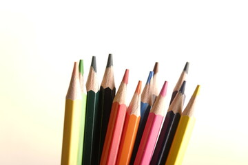 colored pencils against the background of a desk, notebook, white wall