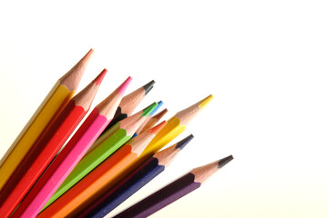 colored pencils against the background of a desk, notebook, white wall