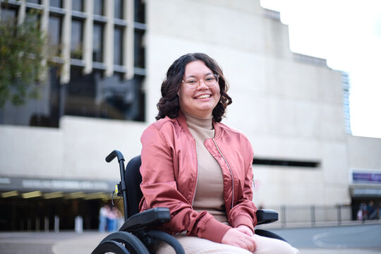 Smiling woman with a disability sitting in a wheelchair outside