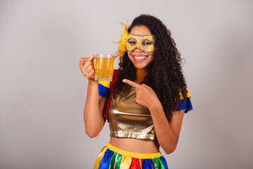 Beautiful black Brazilian woman, with frevo clothes, carnival. in mascara, showing glass of beer,...