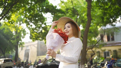 Fototapeta premium Portrait of Asian with bouquet flowers, Vietnamese woman girl traveling in Hanoi urban city town, Vietnam. People lifestyle.