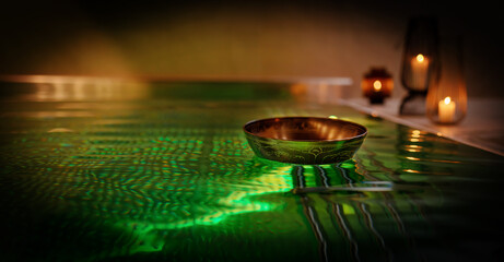 Tibetan bowl on the surface of the pool. Water relaxation and deep meditation.