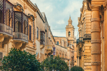 Old medieval town Mdina with Saint Paul cathedral and yellow stone buildings with balcony, Malta