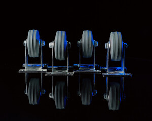 Rubber wheels in a metal frame on a black background with a reflection on the table.