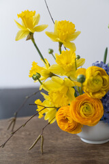 Arrangement with yellow ranunculus and narcissus flowers on japanese eco holder kenzan in vase. Easter holiday concept.