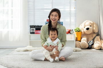 Happy mom and baby boy sitting on carpet smile and cheerful spending time for good moment together...