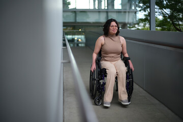 Smiling woman with a disability sitting in a wheelchair going down an accessible ramp