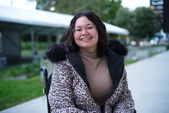Smiling woman with a disability sitting in a wheelchair outside