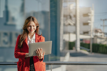 Fototapeta premium young woman using his laptop with smile while standing outdoors.