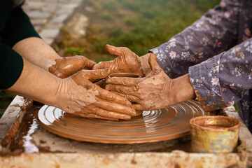 Pottery training. Two pairs of female hands over a potter's wheel in liquid clay. Harmonious contact between master and student