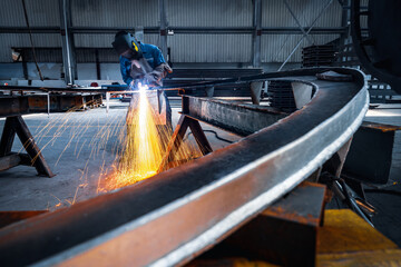 Welder use carbon air arc gouging for hot work cutting or gouging heavy metal steel structure in the fabrication factory.