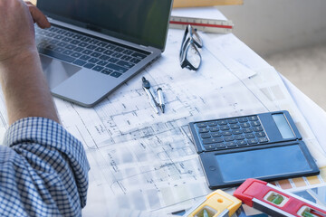 Architect concept, Architects working with blueprints in the office Business accessories (laptop, smartphone, pens, magnifier), accessories for drawing (plans, rulers) and learning on the table