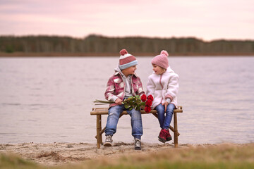 zwei Kinder sitzen am See