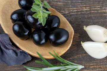 olives with spices and rosemary in a wooden spoon