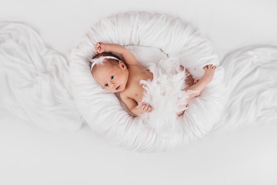 sweet newborn baby in dress with feathers