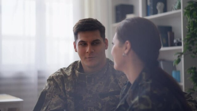 Handsome military man and pretty woman talking in room, smiling and flirting