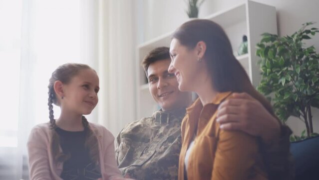 Happy serviceman enjoying family time with wife and little daughter at home