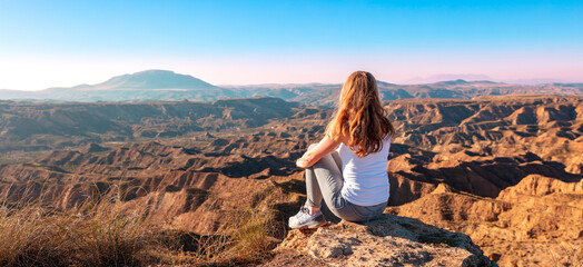 Woman sitting and looking at sunset Gorafe desert in Spain - obrazy, fototapety, plakaty
