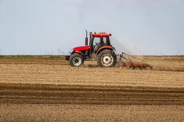 Fototapeta premium Springtime seeding preparations, tractor at work on the fertile fields
