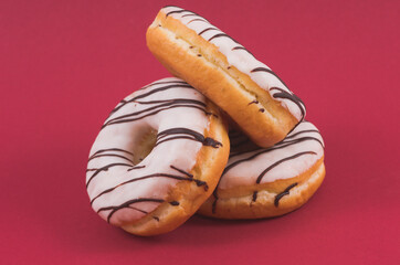 Three glazed sweet doughnuts on red background - 559360993