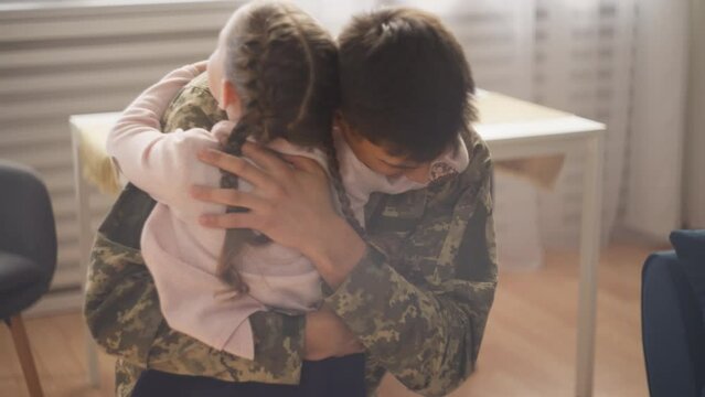 Happy serviceman hugging excited little daughter after long separation, family